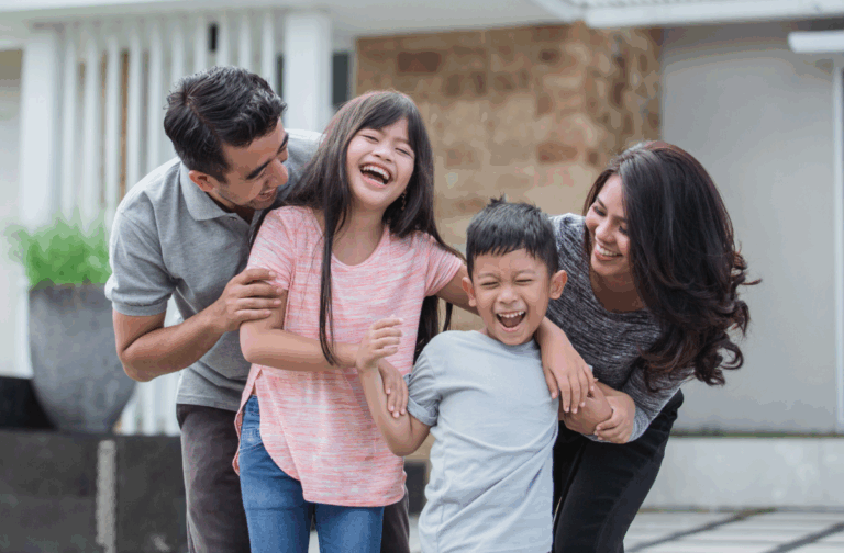 Family laughing in front of house